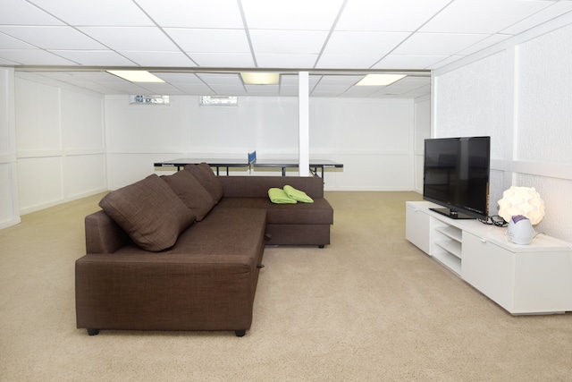 living area featuring light carpet and a drop ceiling