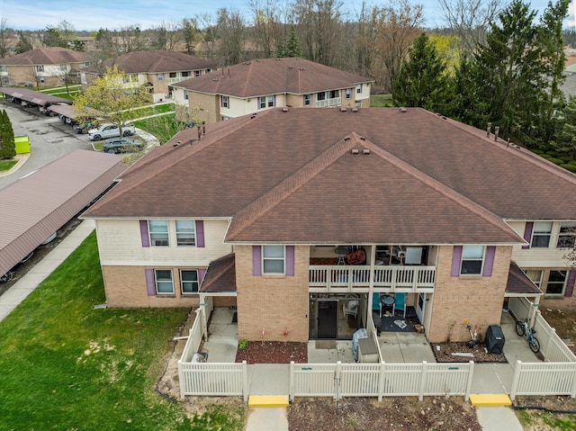 61161 Greenwood Dr, South Lyon, MI 48178 - rear view of house with roof with shingles, a fenced front yard, brick siding, a gate, and a balcony