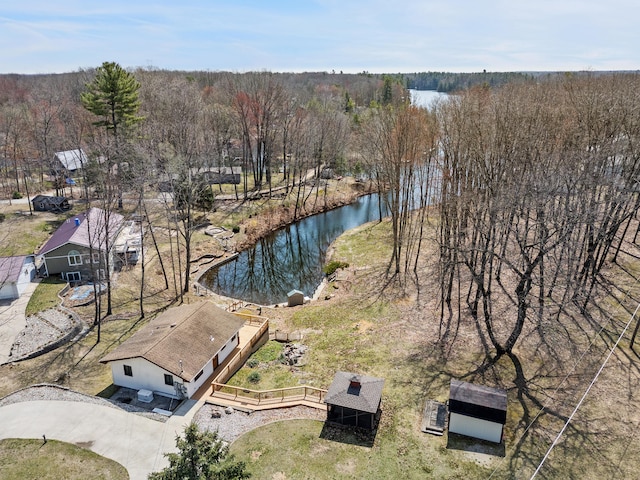 drone / aerial view with a wooded view and a water view