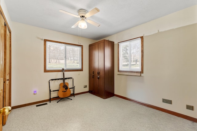 unfurnished bedroom featuring light colored carpet, a closet, baseboards, visible vents, and a ceiling fan