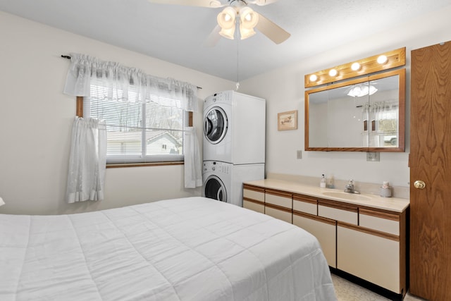 bedroom featuring stacked washer / drying machine, a sink, and ceiling fan