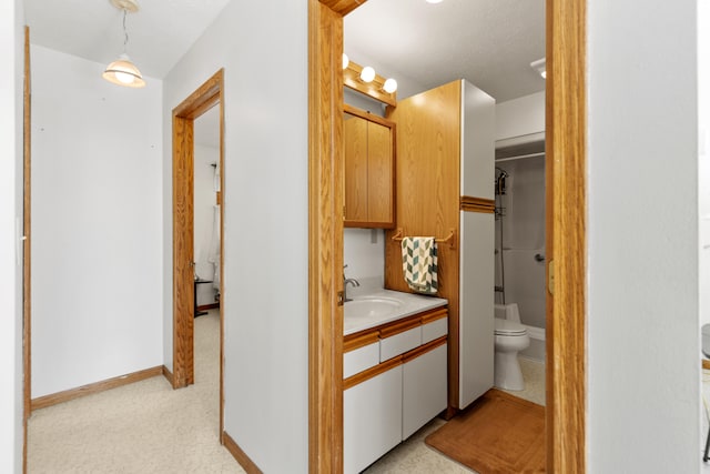 hallway featuring baseboards and a sink