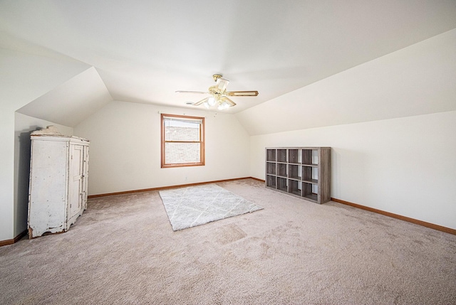 additional living space with light colored carpet, a ceiling fan, vaulted ceiling, and baseboards