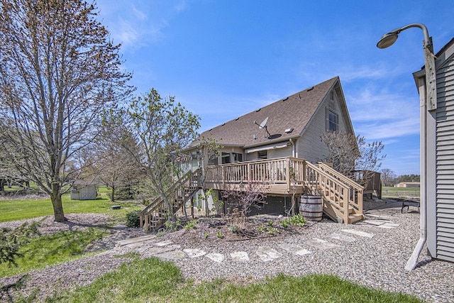 back of property featuring a wooden deck, a shingled roof, and stairs