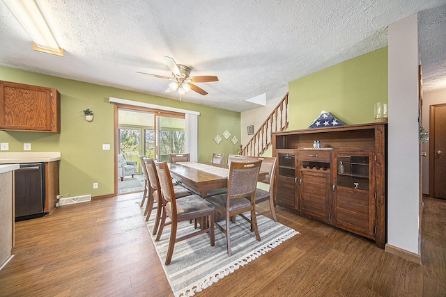 dining space with stairs, light wood finished floors, visible vents, a ceiling fan, and a textured ceiling