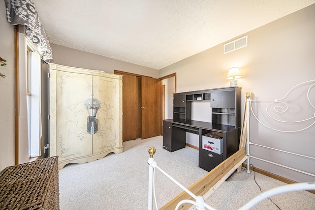 interior space featuring a textured ceiling, visible vents, carpet floors, and baseboards
