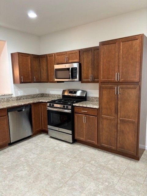 kitchen with light stone countertops, stainless steel appliances, and recessed lighting