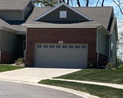 view of front facade featuring brick siding, driveway, and a front yard