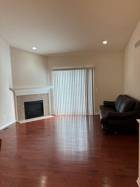 living area with recessed lighting, visible vents, a tiled fireplace, and wood finished floors