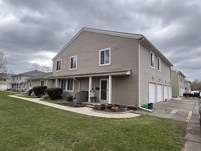 1196 Leisure Dr, Flint, MI 48507 - back of house featuring a yard, driveway, central AC unit, and a garage