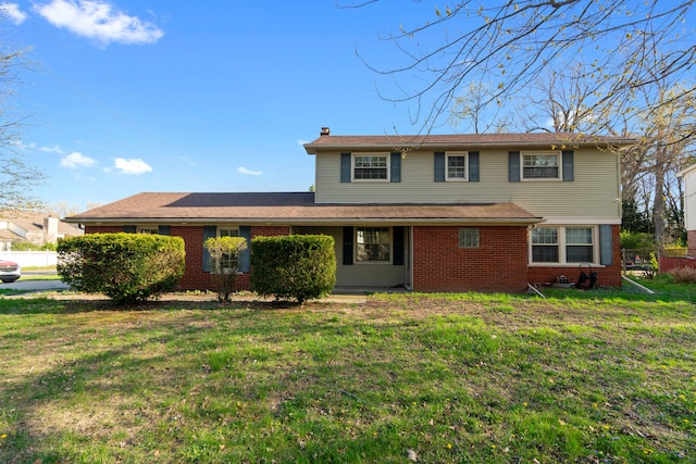 traditional-style home featuring a chimney, a front lawn, and brick siding