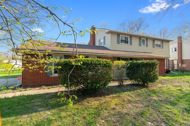 view of front facade featuring brick siding, a chimney, and a front yard