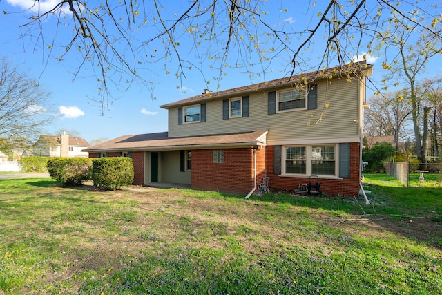 rear view of house with a lawn, fence, and brick siding