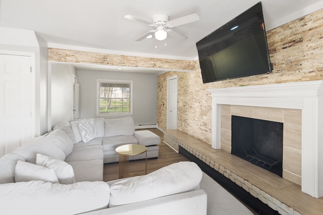 living area featuring wood finished floors, a ceiling fan, a baseboard heating unit, and a fireplace