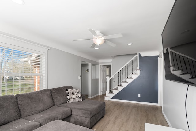 living area with baseboards, a ceiling fan, stairs, and wood finished floors