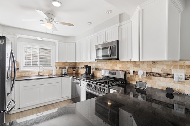 kitchen featuring a sink, appliances with stainless steel finishes, white cabinets, and backsplash