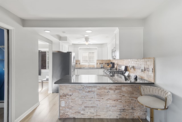 kitchen featuring a sink, light wood-style floors, range, white cabinetry, and stainless steel microwave