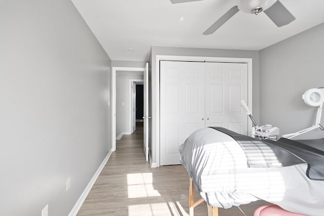 bedroom with light wood-style floors, baseboards, ceiling fan, and a closet