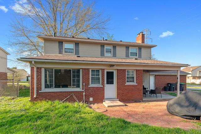 rear view of property with fence, brick siding, a chimney, a patio, and a yard