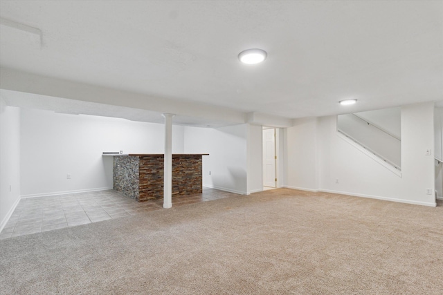finished basement featuring stairway, carpet floors, baseboards, and tile patterned floors