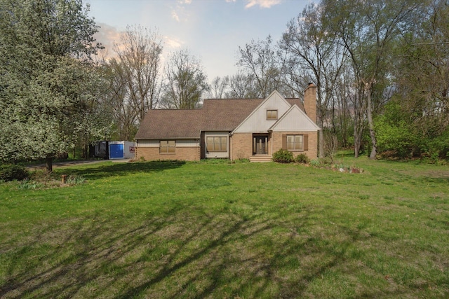 view of front of house with brick siding, a chimney, and a front lawn
