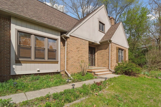 view of front of property featuring brick siding, a shingled roof, and a front yard
