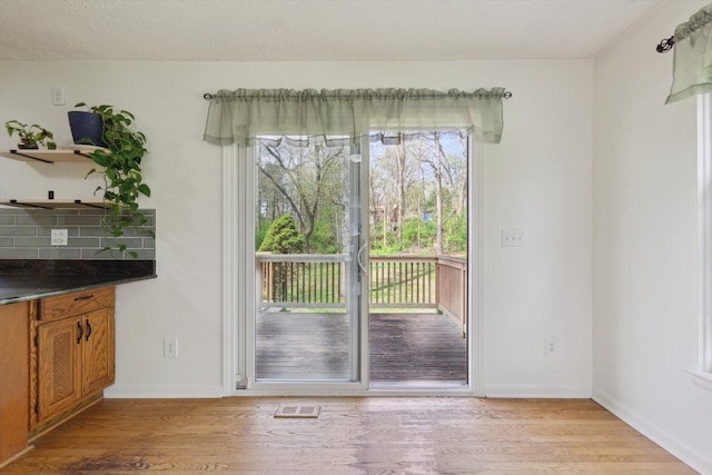 doorway featuring visible vents, light wood-style flooring, and baseboards