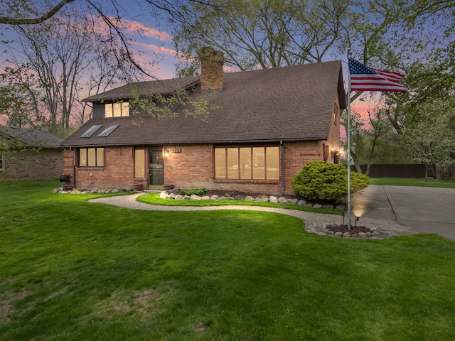 view of front of home with a lawn, a chimney, a shingled roof, and brick siding