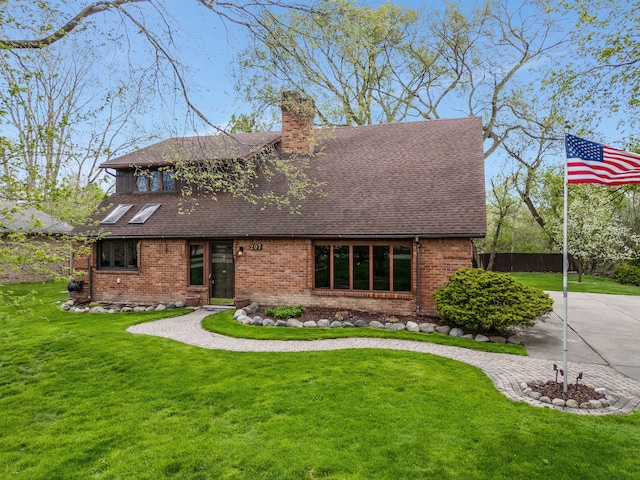 view of front of property featuring brick siding, a shingled roof, a front yard, and a chimney