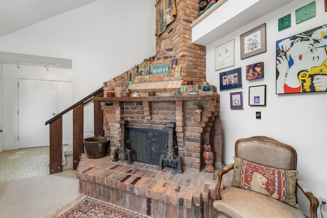 carpeted living area with stairs, track lighting, and a fireplace