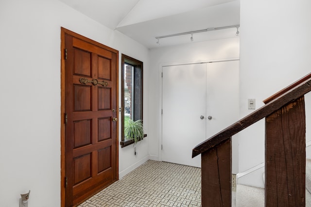 foyer featuring rail lighting, baseboards, and stairs