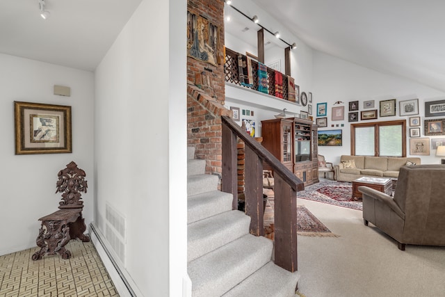 stairs featuring carpet floors, a baseboard radiator, rail lighting, and high vaulted ceiling