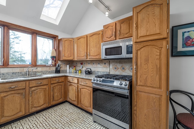 kitchen with a sink, appliances with stainless steel finishes, tasteful backsplash, and rail lighting
