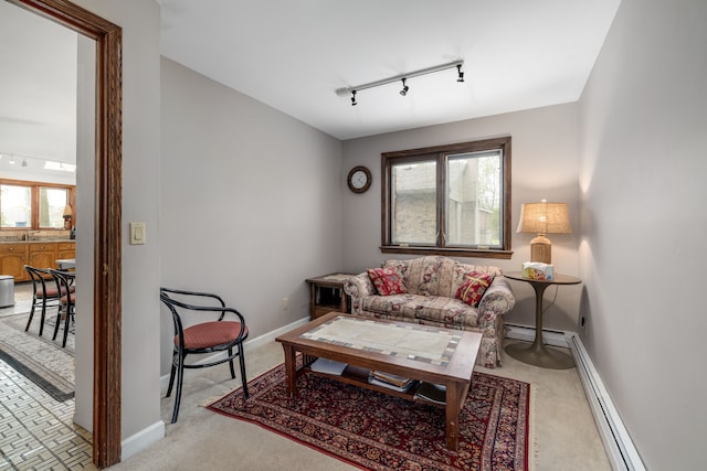 carpeted living area with a healthy amount of sunlight, baseboards, a baseboard heating unit, and rail lighting