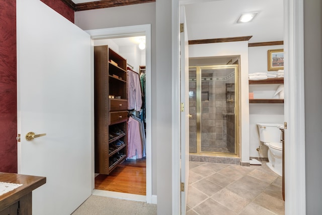 bathroom with toilet, baseboards, ornamental molding, and a stall shower