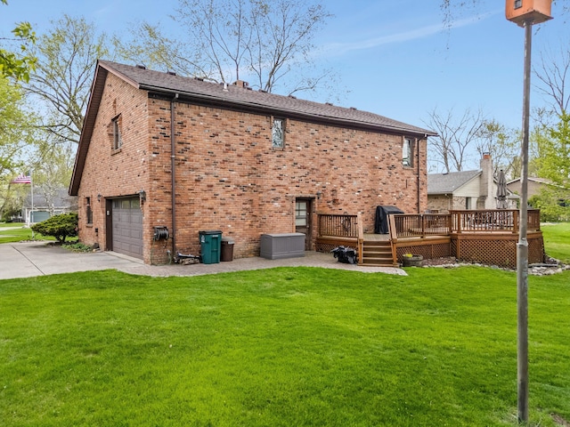 rear view of property featuring driveway, a deck, brick siding, an attached garage, and a yard