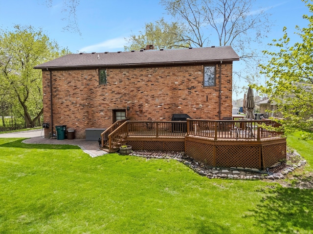 rear view of property featuring brick siding, a yard, and a deck