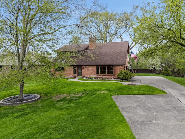view of front of property with a shingled roof, a front lawn, brick siding, a chimney, and concrete driveway