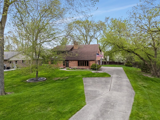 cape cod house featuring a chimney, brick siding, a front lawn, concrete driveway, and a shingled roof