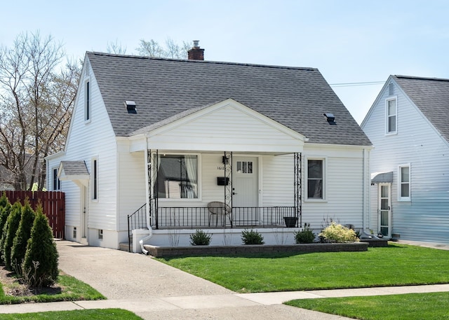 view of front of house featuring roof with shingles, fence, a front lawn, a chimney, and covered porch
