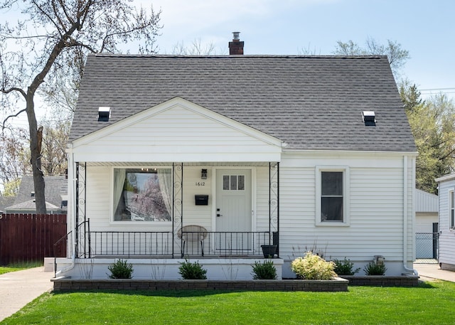 view of front of home featuring roof with shingles, fence, covered porch, and a chimney