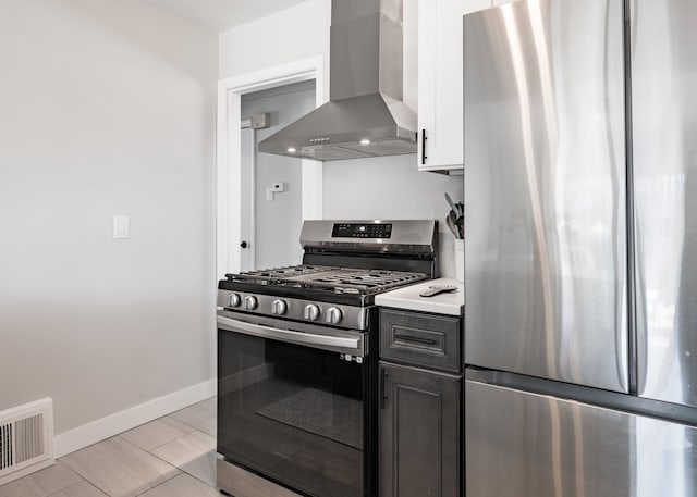 kitchen featuring appliances with stainless steel finishes, light countertops, wall chimney exhaust hood, baseboards, and visible vents