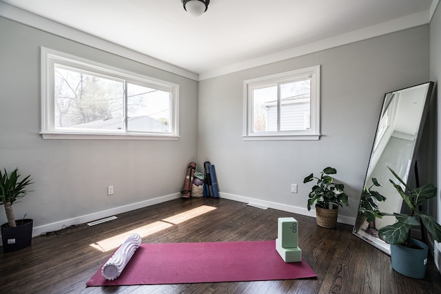 workout area featuring baseboards, visible vents, and wood finished floors