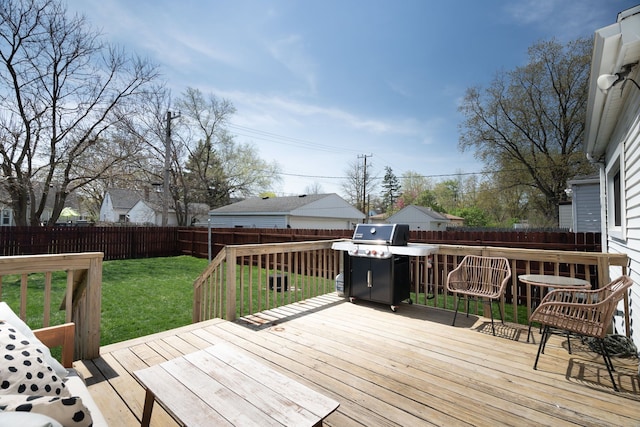 deck featuring a fenced backyard, a lawn, and a grill