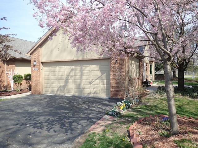 46980 Country Ln Unit 8, Macomb, MI 48044 - view of home's exterior featuring roof with shingles, an attached garage, aphalt driveway, and brick siding