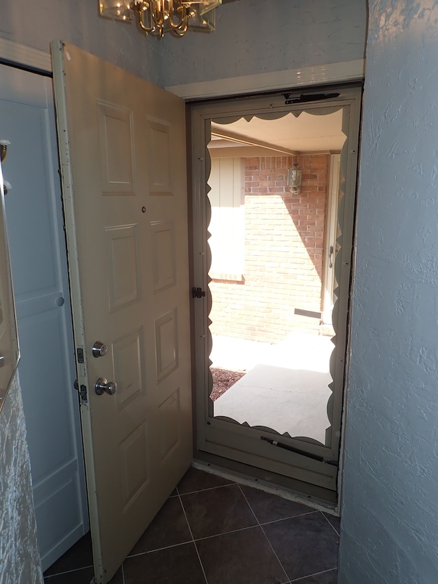 46980 Country Ln Unit 8, Macomb, MI 48044 - doorway with dark tile patterned flooring, a textured wall, and an inviting chandelier