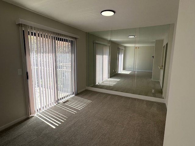 spare room featuring carpet floors and baseboards