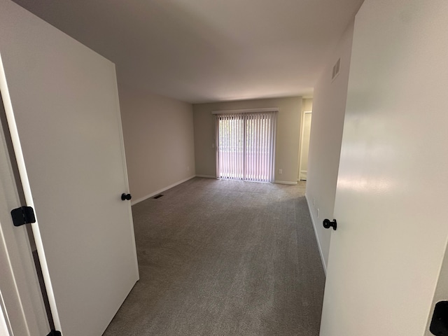 spare room featuring carpet flooring, baseboards, and visible vents