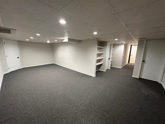 finished below grade area with baseboards, a drop ceiling, and recessed lighting