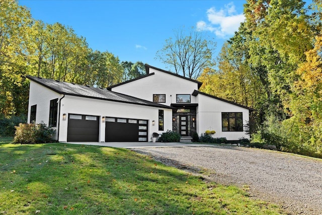 view of front of property featuring a garage, driveway, french doors, and a front yard